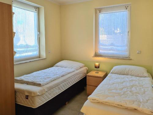 two beds in a room with two windows at Ferienwohnung Seestern Suite im Haus Sonnensegler in Thiessow