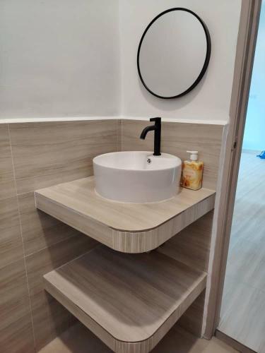 a bathroom sink with a mirror on a wooden shelf at Bayu Beach House in Cherating