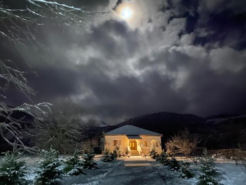 a house in the snow with the moon in the sky at Villa Naum in Voskopojë