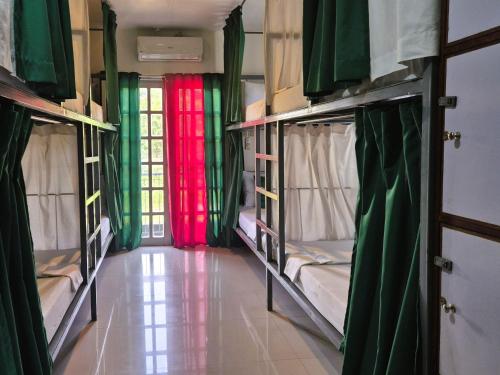 a room with three bunk beds with red and green curtains at Green Turtle Backpackers Guesthouse, Puerto Princesa in Puerto Princesa City