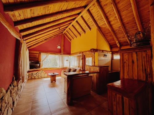 een grote woonkamer met houten plafonds en een bank bij Cabañas Aike in Caviahue