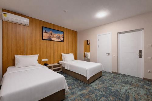 a hotel room with two beds and a closet at Musafir Hotel in Tashkent
