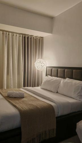 een slaapkamer met een groot bed met gordijnen en een kroonluchter bij Suite Escapes at Brenthill Baguio nr SM and Session Rd in Baguio