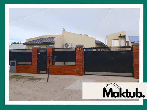 西圣安东尼奥Maktub Alojamiento的一栋房子，前面有黑色栅栏和一块牌子。