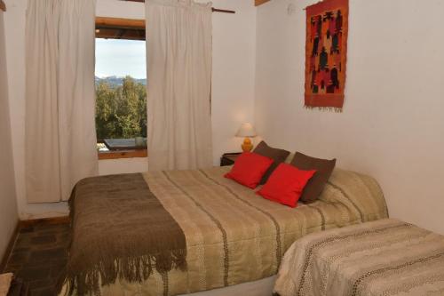 a bedroom with a bed with red pillows and a window at Girgola hospedaje in Villa Pehuenia