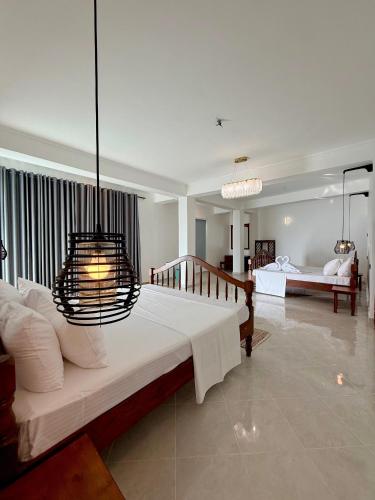 a bedroom with a large bed with a chandelier at Moringa Beach in Mirissa