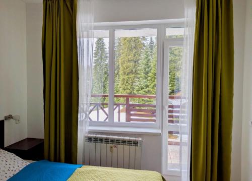een slaapkamer met een raam met uitzicht op een balkon bij STRIM Apartment 406 Stream Resort, Pamporovo in Pamporovo