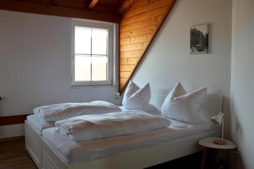 une chambre avec deux lits avec des draps blancs et une fenêtre dans l'établissement Fewo Feldblick, à Merkendorf