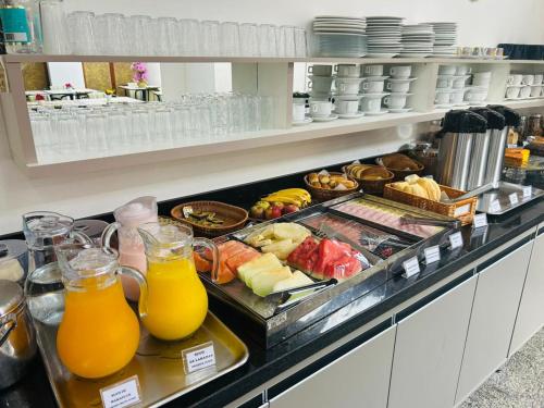 a buffet line with orange juice and other food at Six's Hotel in Jacareí
