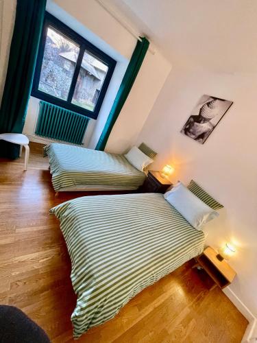 two beds in a room with a window at Château du Vigny - Gîte in Saint-Michel-de-Maurienne