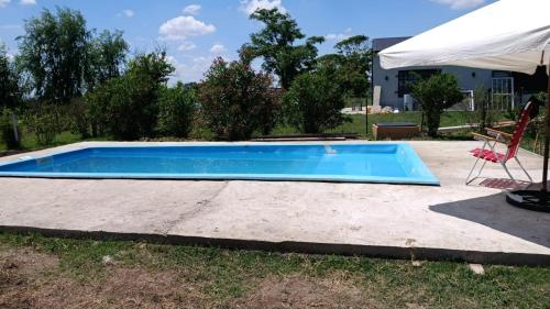 een zwembad met een stoel en een parasol bij Departamentos Los corrales in San Andrés de Giles