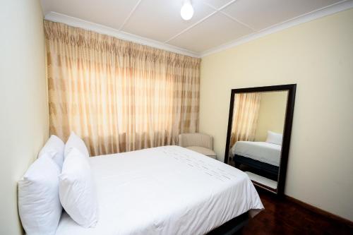 een slaapkamer met een wit bed en een spiegel bij Airport Lodge Hotel in Kempton Park