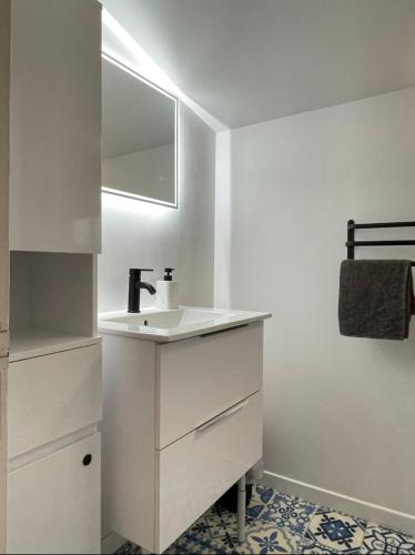 une salle de bains blanche avec un lavabo et un miroir dans l'établissement Duplex Hyper Center Dieppe, à Dieppe
