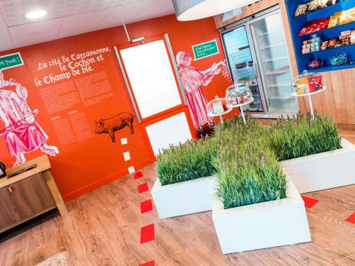 a store with three potted plants in front of a door at ibis Styles Carcassonne La Cité in Carcassonne