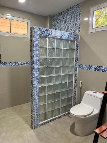 a bathroom with a toilet and a glass shower at Baan Ob-oun Homestay in Ban Khlong Chi Lat