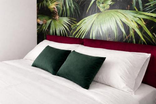 un letto bianco con due cuscini verdi di Maison Gucci a Milano