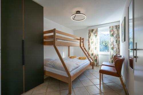 een slaapkamer met een stapelbed en een stoel bij Zuhause in den Alpen Ihre Ferienwohnung mit Hallenbad und Sauna in Lenzerheide