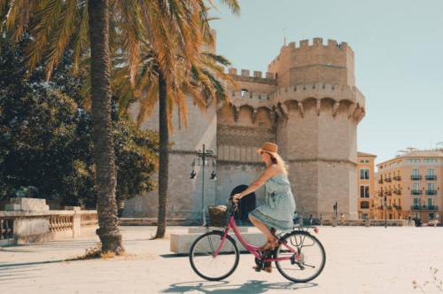 Una donna che va in bicicletta davanti a un castello. di Loft acogedor junto al Roig Arena a Valencia