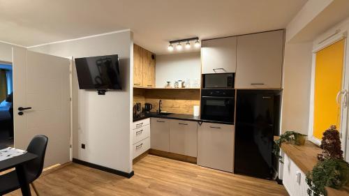 a kitchen with white cabinets and a black refrigerator at W Centrum in Piła