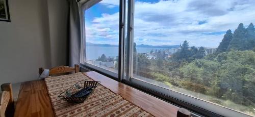 een kamer met een groot raam met uitzicht op het water bij El encanto del lago in Bariloche