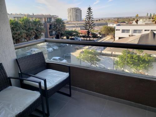 a balcony with two chairs and a view of a city at Zapahuira in Arica