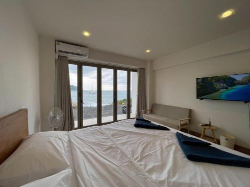 een slaapkamer met een groot bed en een groot raam bij Acacia Phuket in Nai Harn Beach