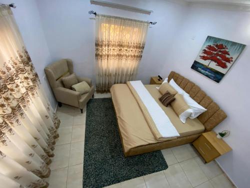 a bedroom with a large bed and a chair at Flamingo 1 spacious solar powered 2 bedroom home with a stocked ready kitchen in Jos
