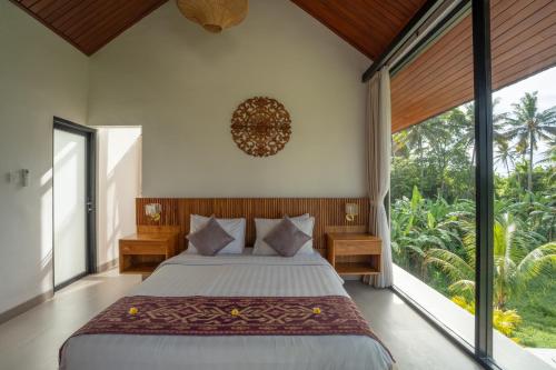 a bedroom with a large bed and large windows at Waringin Villa Ubud in Ubud