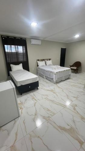 two beds in a room with a marble floor at Pousada Encanto Dos Colibris in Martins