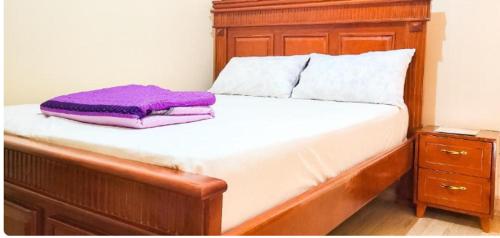 een bed met een houten hoofdeinde en een paars kussen bij Icon Hotel in Kampala