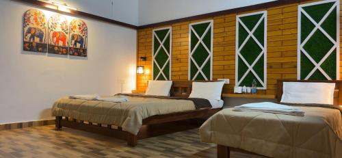 2 bedden in een kamer met glas-in-loodramen bij Hatti Eden Coorg in Gonikoppal