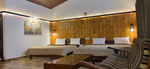 een hotelkamer met twee bedden en een bank bij Hatti Eden Coorg in Gonikoppal
