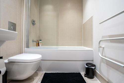 a white bathroom with a tub and a toilet at Stylish 2 Bedroom APT with Balcony in Leeds