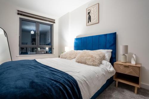 a bed with a blue headboard in a bedroom at Stylish 2 Bedroom APT with Balcony in Leeds