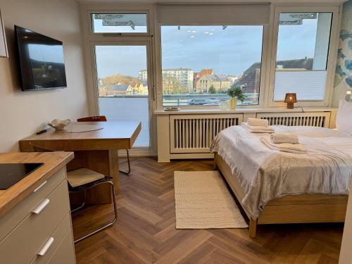 ein Schlafzimmer mit einem Bett und einem Schreibtisch und zwei Fenstern in der Unterkunft Boje in Westerland