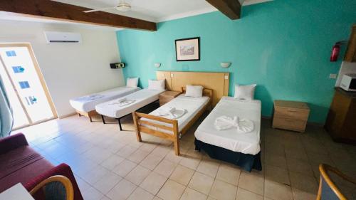 una stanza con tre letti in una stanza con pareti blu di Quad Room 2636 a San Pawl il-Baħar