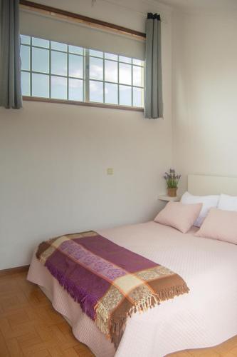 a bedroom with a white bed with a window at Cantinho da Celeste in Paramos