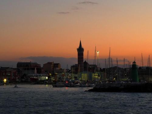 a city skyline with a clock tower at sunset at Brezza di mare home con garage in Civitanova Marche