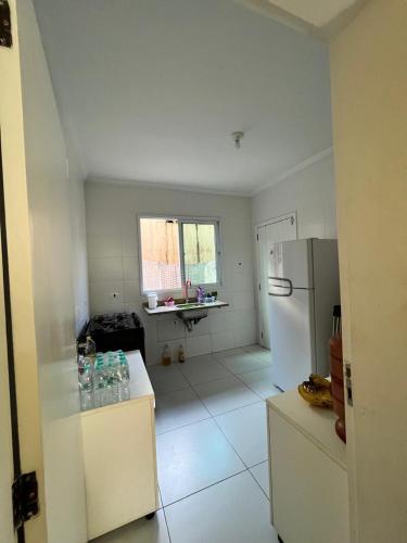 a white kitchen with a refrigerator and a sink at Casa Silva enseada in Guarujá