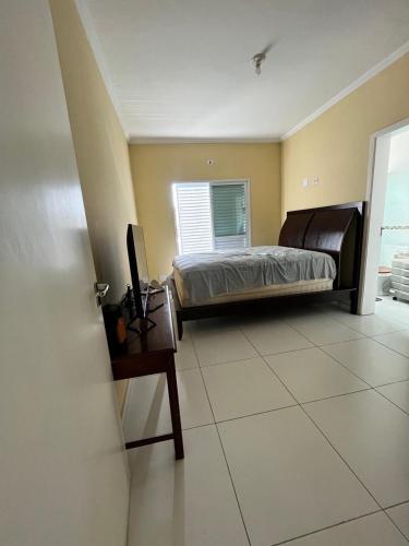 a bedroom with a bed and a desk with a computer at Casa Silva enseada in Guarujá
