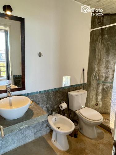 a bathroom with a sink and a toilet and a mirror at Les Diablettes in Punta Del Diablo