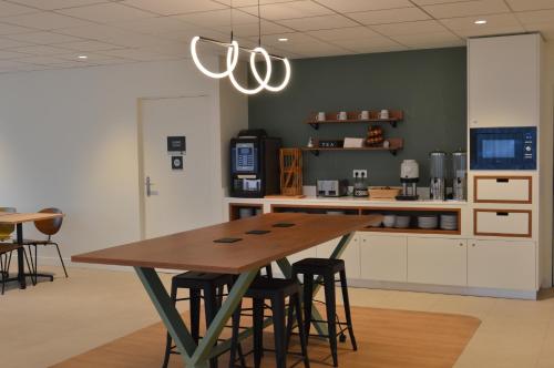 een keuken met een houten tafel en een aantal stoelen bij Kyriad Argenteuil in Argenteuil