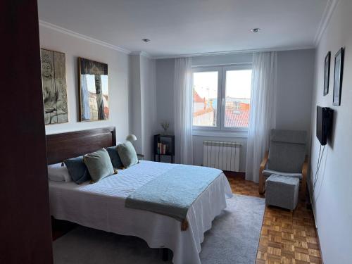 een slaapkamer met een groot bed en een stoel bij A CALZADA in Cambados