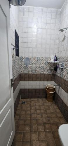 a bathroom with a toilet and a tiled floor at LBS Farms in Coimbatore