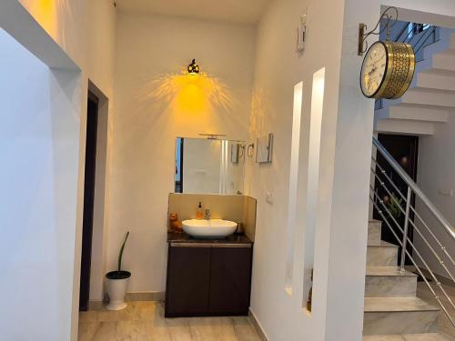 a bathroom with a sink and a clock on the wall at CloudNine Stay in Sultan Bathery