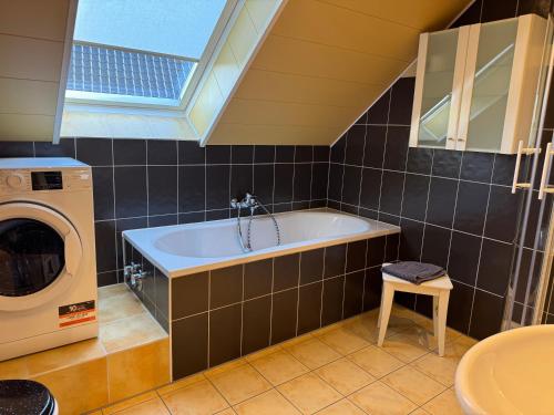 a bathroom with a tub and a washing machine at Eifeleule in Hürtgenwald