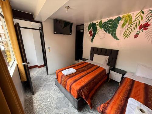 ein Schlafzimmer mit zwei Betten und einem Fernseher darin in der Unterkunft Hostal Mónaco in Machu Picchu