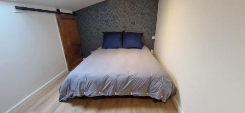 een bed met blauwe kussens in een kleine kamer bij Gîte de Dedette in La Grise