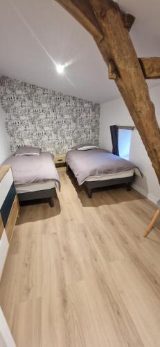 two beds sitting in a room with wooden floors at Gîte de Dedette in La Grise