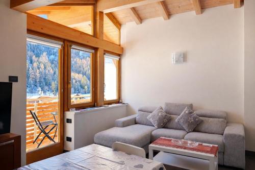 een woonkamer met een bank en een tafel bij Appartamento Mary - Casa Green - Dog friendly, box auto in Cogolo